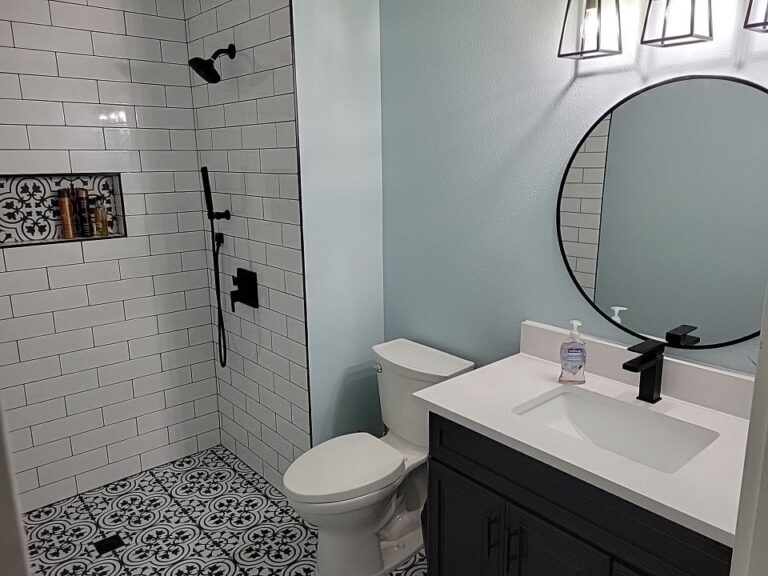 White subway-tile shower with a black-and-white patterned floor and black fixtures
