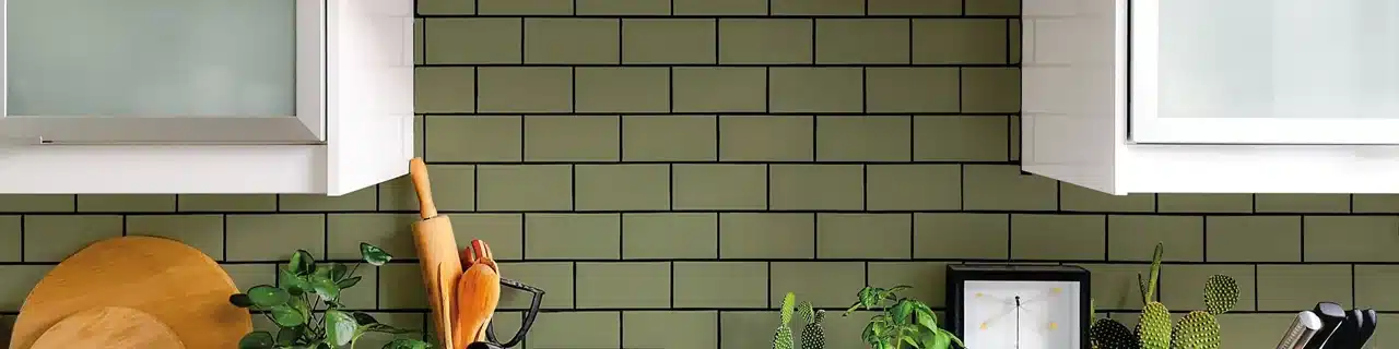 Daltile Color Wheel Classic green subway tile backsplash beneath white kitchen cabinets in a manufacturer scene