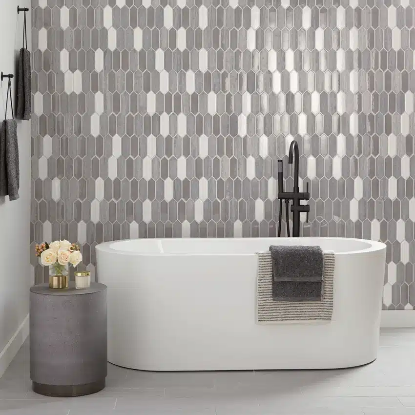 Daltile Fonte Heather Harbor Blend picket mosaic on the wall behind a white bathtub in a manufacturer bathroom scene