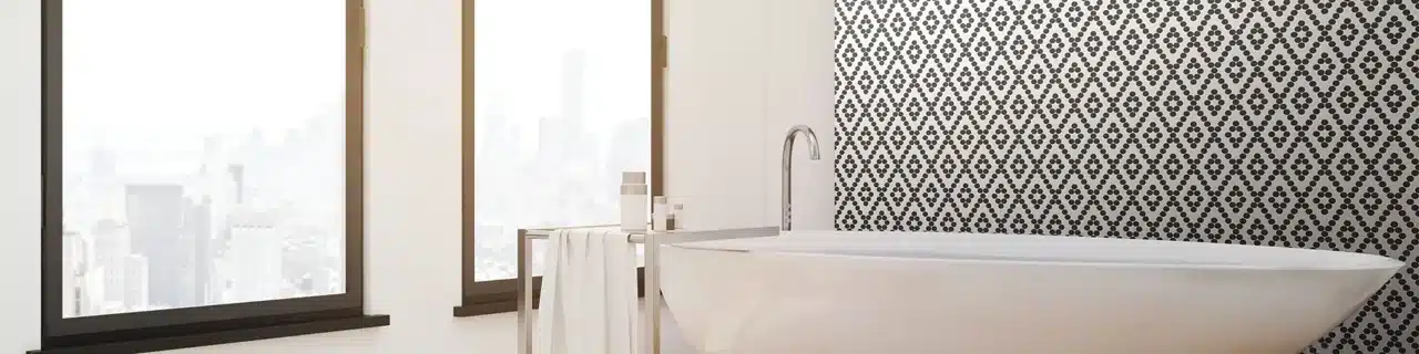 Daltile Keystones black and white penny-round diamond mosaic on a wall behind a freestanding bathtub in a manufacturer scene