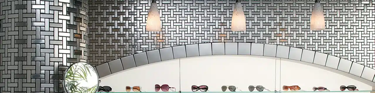 Daltile Metallica Brushed Stainless Steel mosaic wall around an eyewear display niche in a manufacturer retail scene