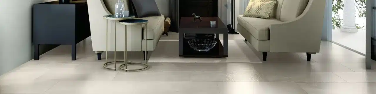 Daltile Slate Attaché Meta White porcelain floor tile beneath cream sofas and a coffee table in a manufacturer living room scene