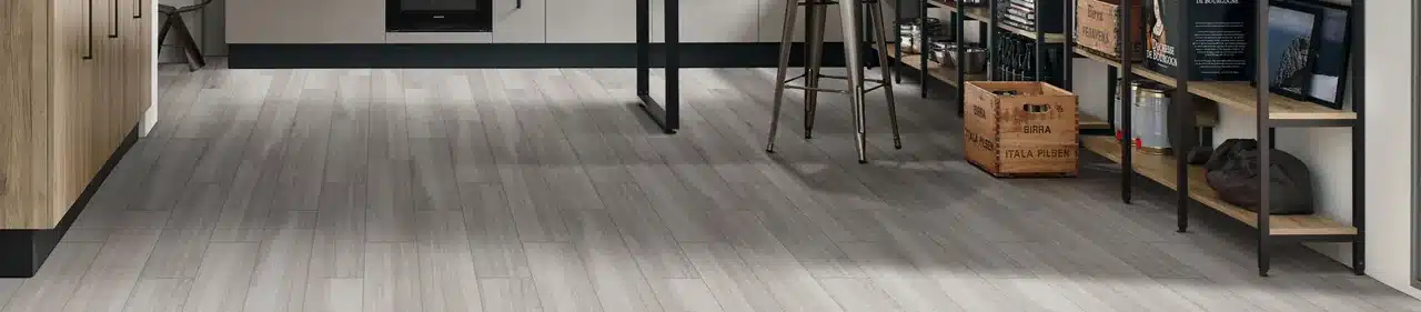 MSI Havenwood gray wood-look porcelain floor beside kitchen cabinetry, stools and open shelving in a manufacturer scene