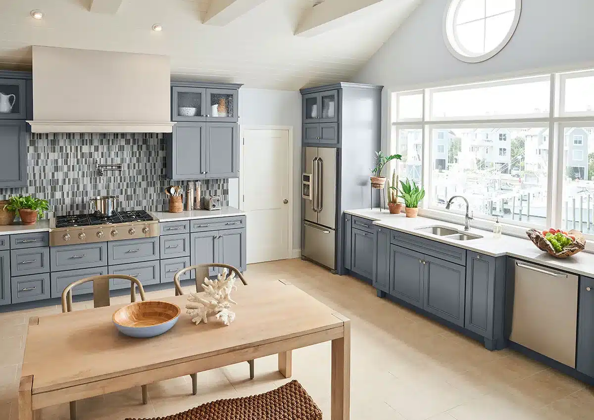MSI Palisades Citi Stax Lapis glass mosaic backsplash behind a range between blue-gray kitchen cabinets in a manufacturer scene