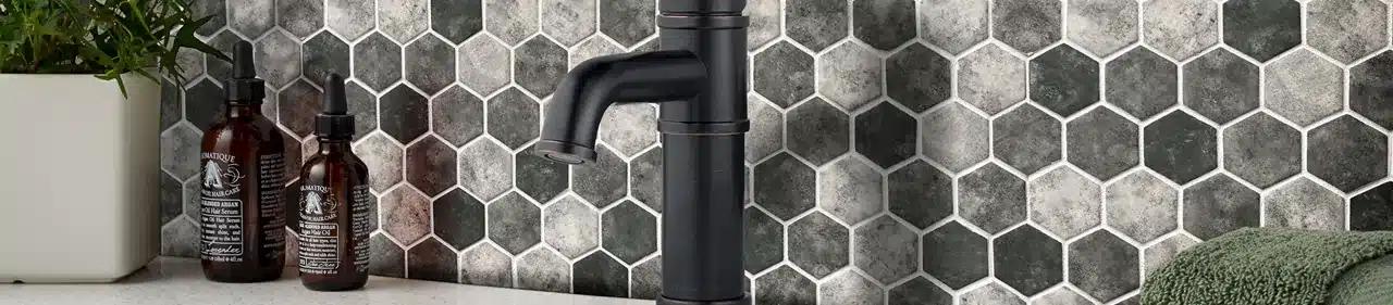 MSI Revaso gray hexagon recycled glass mosaic backsplash behind a black vanity faucet in a manufacturer scene