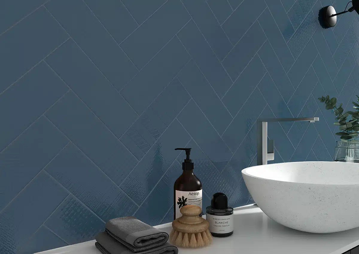 MSI Urbano Navy 3D Mix ceramic tile in a herringbone pattern above a white vessel sink in a manufacturer bathroom scene